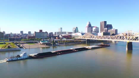 Aerial-Of-Ohio-River-Barge-In-Front-Of-City-Skyline-Of-Louisville,-Kentucky