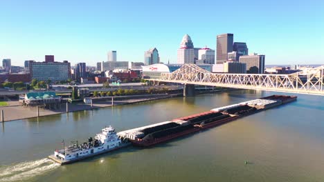 Aerial-Of-Ohio-River-Barge-In-Front-Of-City-Skyline-Of-Louisville,-Kentucky
