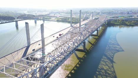 Aerial-Over-Ohio-River-Bridges-With-The-Louisville,-Kentucky-Downtown-Skyline-Distant-Suggests-Infrastructure