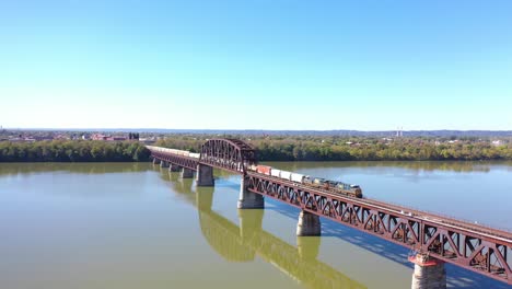 Aerial-Of-A-Freight-Train-Crossing-The-Ohio-River-On-A-Steel-Railway-Bridge-Near-Louisville,-Kentucky