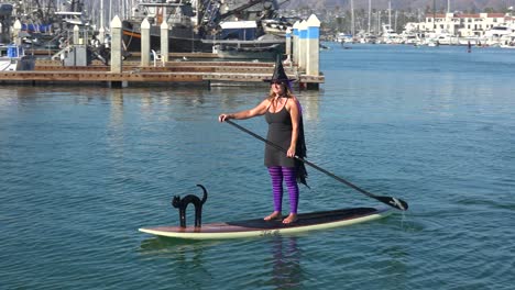 Witches-In-Costume-Paddle-On-Surfboards-And-Paddleboards-To-Celebrate-Halloween-In-Ventura-Harbor,-California