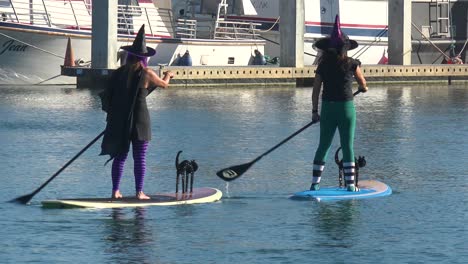 Witches-In-Costume-Paddle-On-Surfboards-And-Paddleboards-To-Celebrate-Halloween-In-Ventura-Harbor,-California