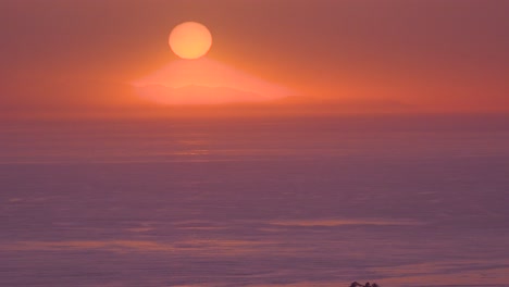 A-Huge-Red-Round-Ball-Of-Sun-At-Sunset-Over-The-Pacific-Ocean-Near-Malibu,-California