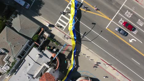 Ukrainische-Demonstranten-Von-Oben-Nach-Unten-Mit-Großer-Ukrainischer-Flagge-Protestieren-Gegen-Die-Russische-Invasion-Ihres-Landes,-Auf-Der-Straße-In-Malibu,-Kalifornien,-Mit-Malibu-Schild
