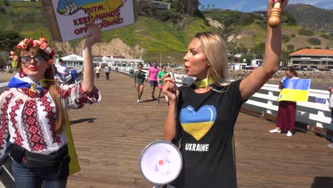Ukrainische-Demonstranten-Von-Oben-Nach-Unten-Mit-Großer-Ukrainischer-Flagge-Protestieren-Gegen-Die-Russische-Invasion-Ihres-Landes,-Auf-Dem-Pacific-Coast-Highway-In-Malibu,-Kalifornien,-Mit-Malibu-Schild