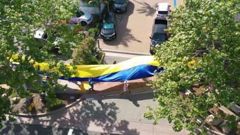 Ukrainische-Antikriegs-Demonstranten-Aus-Der-Luft-Zeigen-Eine-Lange-Flagge-In-Malibu,-Kalifornien,-Um-Gegen-Die-Russische-Invasion-In-Der-Ukraine-Zu-Protestieren