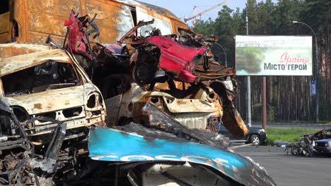 Wrecked-And-Burned-Cars-Stacked-In-The-Car-Cemetery-With-Welcome-To-Irpin,-Ukraine-Billboard-In-Background