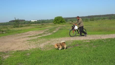 Ein-Alter-Mann-Geht-Mit-Seinem-Hund-Und-Seinem-Fahrrad-In-Der-Ländlichen-Ukraine-Auf-Einem-Feld-Spazieren