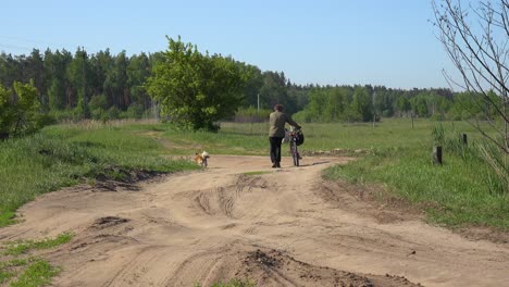 Un-Anciano-Camina-En-Un-Campo-Con-Su-Perro-Y-Su-Bicicleta-En-La-Ucrania-Rural