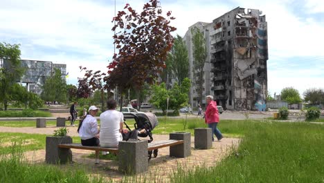 People-Walk-Through-A-Devastated-Park-In-Borodianka,-Borodyanka,-Ukraine-With-Bombed-And-Rocketed-Apartment-Buildings-Where-Hundreds-Were-Killed-By-Russian-Occupation