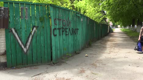 Una-Valla-A-Lo-Largo-De-Una-Calle-En-Ucrania-Está-Desfigurada-Con-Vandalismo-De-Graffiti-Ruso-V-Y-La-Frase-&quot;dejen-De-Disparar,-Disparan&quot;