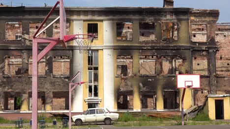 Un-Edificio-Escolar-Gravemente-Dañado-Con-Cancha-De-Baloncesto-En-Primer-Plano-En-Saltivka,-Kharkiv,-Ucrania