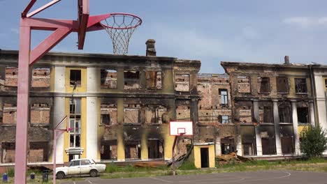Ein-Stark-Beschädigtes-Schulgebäude-Mit-Basketballplatz-Im-Vordergrund-In-Saltivka,-Charkiw,-Ukraine