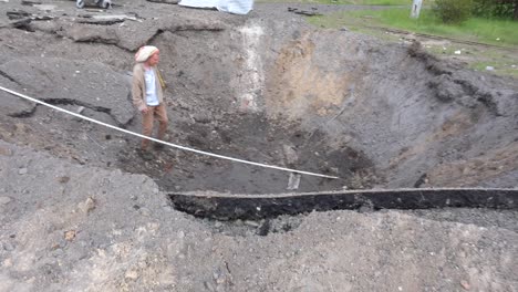 A-Man-Walks-Into-A-Huge-Bomb-Crater-From-A-Russian-Missile-Or-Rocket-Attack-On-Kyiv,-Ukraine