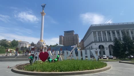 Arbeiter-Pflanzen-Auf-Dem-Unabhängigkeitsplatz-Mit-Der-Maidan-Statue-Und-Dem-Hotel-Ukraine-Im-Hintergrund