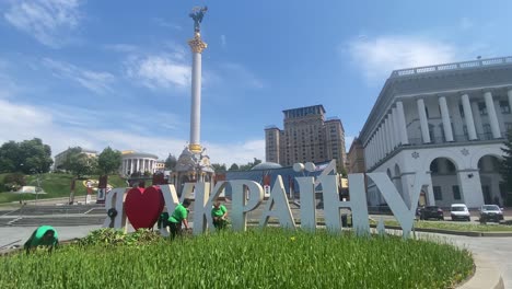 Arbeiter-Pflanzen-Auf-Dem-Unabhängigkeitsplatz-Mit-Der-Maidan-Statue-Und-Dem-Hotel-Ukraine-Im-Hintergrund