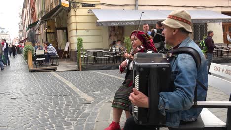Dúo-Musical-Tradicional-Toca-Violín-Y-Acordeón-En-La-Calle-En-El-Casco-Antiguo-De-Lviv,-Ucrania