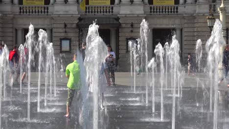 Children-Play-In-The-Dancing-Fountains-Outside-The-Majestic-Opera-House-In-Central-Lviv,-Ukraine