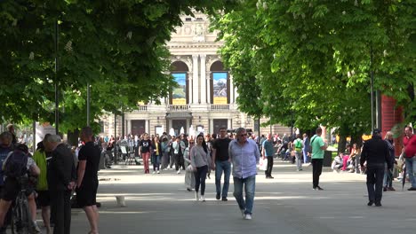 Multitudes-Urbanas-De-Ucranianos-Caminan-Por-El-Carril-Sombreado-Del-Parque-Con-Fondo-De-ópera-En-El-Centro-De-Lviv,-Ucrania