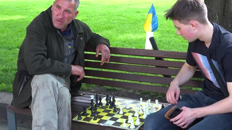 Two-Men-Play-Chess-On-A-Bench-In-The-Park-In-Central-Lviv,-Ukraine