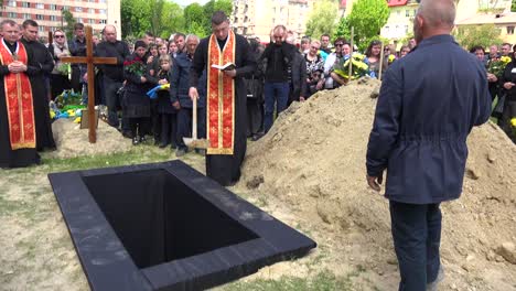 Un-Sacerdote-Palea-Tierra-Fresca-En-Una-Tumba-Abierta-En-Un-Cementerio-En-Lviv,-Ucrania-Durante-El-Funeral-De-Un-Soldado