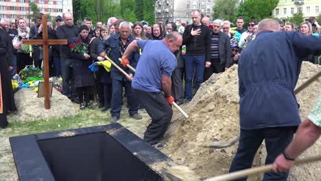 Trabajadores-Palean-Tierra-Fresca-En-Una-Tumba-Abierta-En-Un-Cementerio-En-Lviv,-Ucrania-Durante-El-Funeral-De-Un-Soldado
