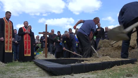 Trabajadores-Palean-Tierra-Fresca-En-Una-Tumba-Abierta-En-Un-Cementerio-En-Lviv,-Ucrania-Durante-El-Funeral-De-Un-Soldado