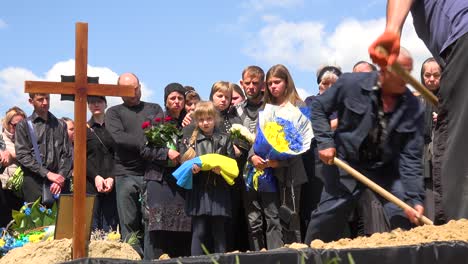 Una-Hermosa-Niña-Sostiene-Una-Bandera-Ceremonial-Con-Su-Familia-En-El-Funeral-De-Su-Padre-En-Lviv,-Ucrania