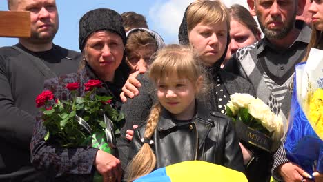 Una-Hermosa-Niña-Sostiene-Una-Bandera-Ceremonial-Con-Su-Familia-En-El-Funeral-De-Su-Padre-En-Lviv,-Ucrania