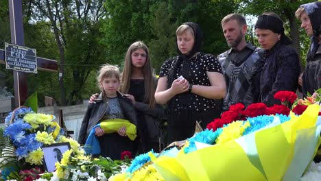 Ein-Schönes-Mädchen-Hält-Mit-Ihrer-Familie-Bei-Der-Beerdigung-Ihres-Vaters-In-Lemberg,-Ukraine,-Eine-Zeremonielle-Flagge