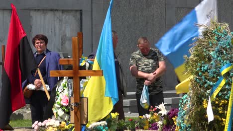 Patriotische-Ukrainische-Flaggen-Wehen-Auf-Einem-Friedhof-Zu-Ehren-Der-Opfer-Des-Krieges-In-Der-Ukraine,-Während-Die-Besucher-Zuschauen