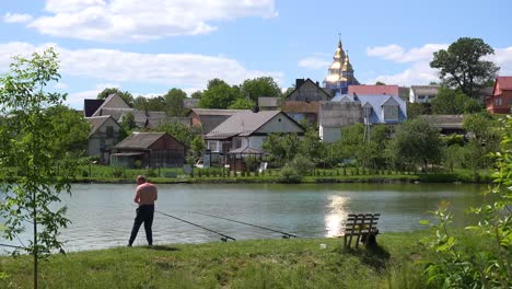 A-Shirtless-Ukrainian-Man-Relaxes-And-Fishes-Near-A-Lake-In-A-Small-Town-In-Western-Ukraine