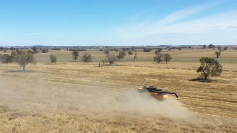 An-Excellent-Aerial-Shot-Of-A-Farming-Combine-Raising-Dust-And-Cutting-Through-A-Field-In-Parkes,-New-South-Wales,-Australia