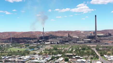 Excellent-Aerial-Shot-Of-Traffic-Near-The-Smokestacks-Of-An-Industrial-Center-In-Mount-Isa,-Australia