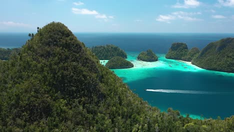 Excellent-Aerial-Shot-Of-A-Motorboat-Speeding-Past-The-Wayag-Islands,-Raja-Ampat,-Indonesia