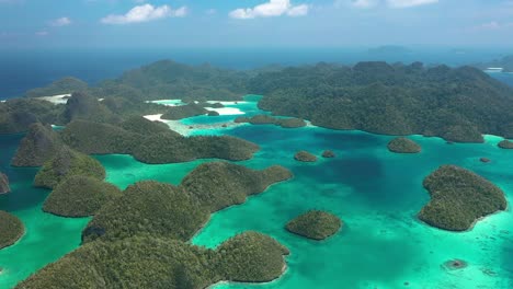 Excellent-Aerial-Shot-Of-The-Wayag-Islands,-Raja-Ampat,-Indonesia,-With-The-Shadows-Of-Passing-Clouds-Visible-In-The-Clear-Blue-Water