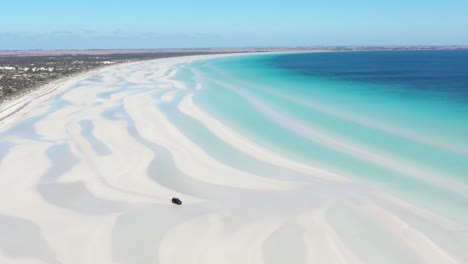 Excellent-Aerial-Shot-Of-A-Van-Driving-On-The-White-Sands-Of-Flaherty-Beach-Near-Clear-Blue-Waters