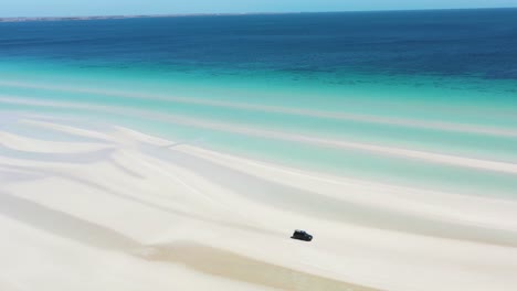 Excellent-Aerial-Shot-Of-A-Van-Driving-Along-The-Shoreline-White-Sands-Of-Flaherty-Beach-Near-Clear-Blue-Waters