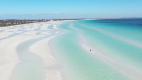 Excellent-Aerial-Shot-Of-A-Person-Standing-On-The-White-Sands-Of-Flaherty-Beach,-Near-Clear-Blue-Water,-On-Yorke-Peninsula,-Australia