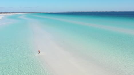 Excellent-Aerial-Shot-Of-A-Man-Running-Through-The-White-Sandy-Beaches-And-Clear-Blue-Water-Of-Flaherty-Beach-On-Yorke-Peninsula,-Australia