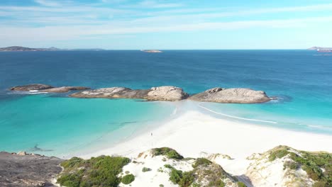 Excellent-Aerial-Shot-Of-A-Tourist-Jogging-On-The-White-Beach-By-Clear-Blue-Water-In-Wylie-Bay,-Esperance,-Australia