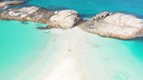 Excellent-Aerial-Shot-Of-A-Tourist-Standing-Among-White-Sand-And-Clear-Blue-Surf-In-Wylie-Bay,-Esperance,-Australia