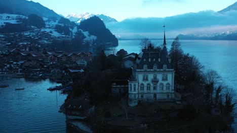 Hervorragende-Luftaufnahme-Des-Schlosses-Auf-Der-Halbinsel-Iseltwald,-Schweiz-In-Der-Abenddämmerung