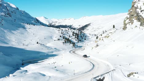 Excelente-Vista-Aérea-De-Un-Coche-Conduciendo-Por-Una-Carretera-Nevada-De-Davos-A-St-Moritz,-Suiza