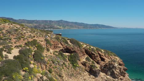 Excellent-Aerial-View-Of-Tourists-Climbing-Along-A-Rocky-Coastline-In-Malibu,-California