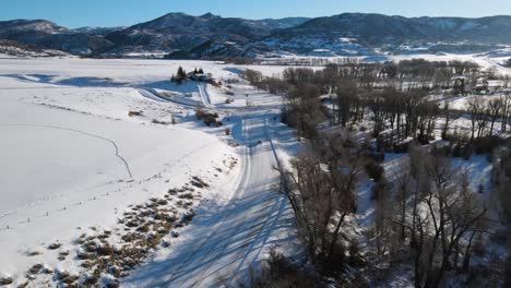 Ausgezeichnete-Luftaufnahme-Eines-Autos,-Das-Auf-Einer-Verschneiten-Straße-In-Richtung-Steamboat-Springs,-Colorado,-Fährt