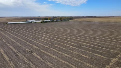 Aerial-Drone-Footage-Of-Dormant-Fields,-Farm-Buildings-And-A-Farmhouse-Under-Blue-Skies-In-Rural,-Midwestern-Iowa