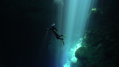 A-Diver-Swims-Out-Of-A-Beam-Of-Light-Into-Darkness-Off-The-Coast-Of-Mexico'S-Yucatan-Peninsula
