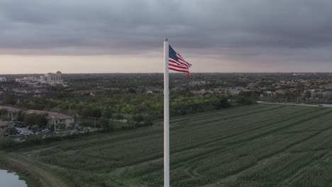 Ausgezeichnete-Luftaufnahme-Der-Amerikanischen-Flagge,-Die-über-Landwirtschaftlichen-Feldern-Im-Südlichen-Florida-Weht