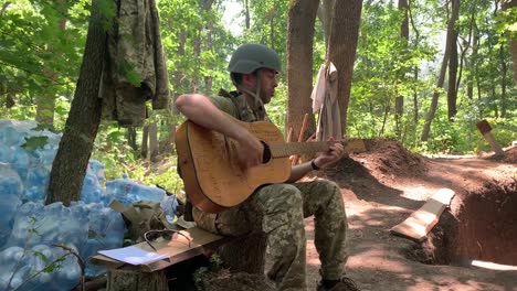 A-Ukrainian-Soldier-Plays-Guitar-In-The-Trenches-On-The-Frontline-In-Donbas,-Ukraine